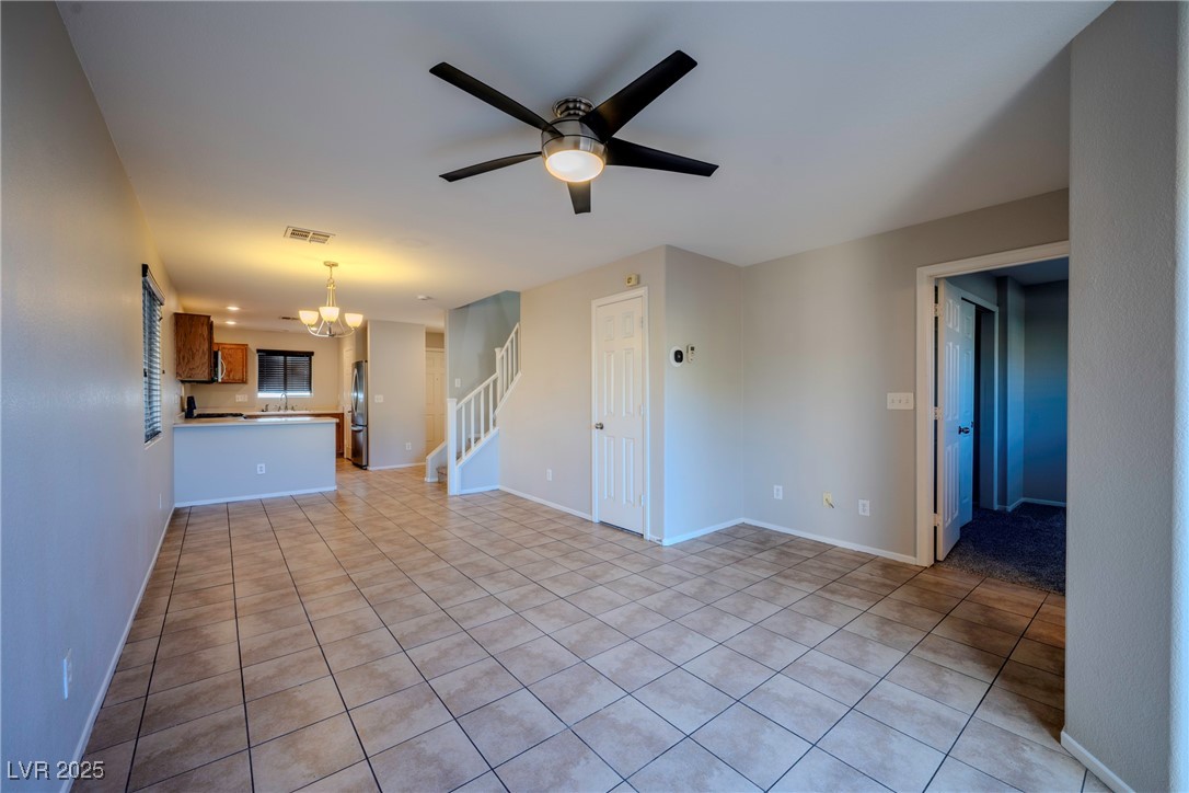5283 Broadlake Lane Las Vegas, NV 89122 - Photo 28 of 36 Unfurnished living room featuring light tile patterned floors, stairs, ceiling fan, and a chandelier