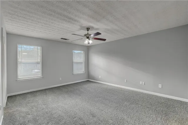 an empty room with windows and chandelier fan