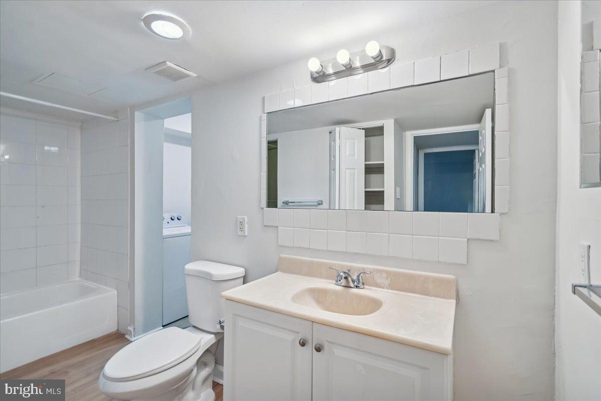 9200 Edwards Way, Unit 1202 Hyattsville, MD 20783 - Photo 16 of 34 a bathroom with a toilet a sink a mirror a bathtub and vanity