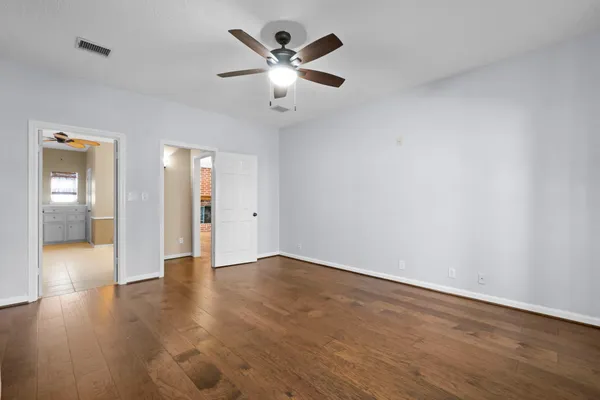 an empty room with wooden floor and a ceiling fan