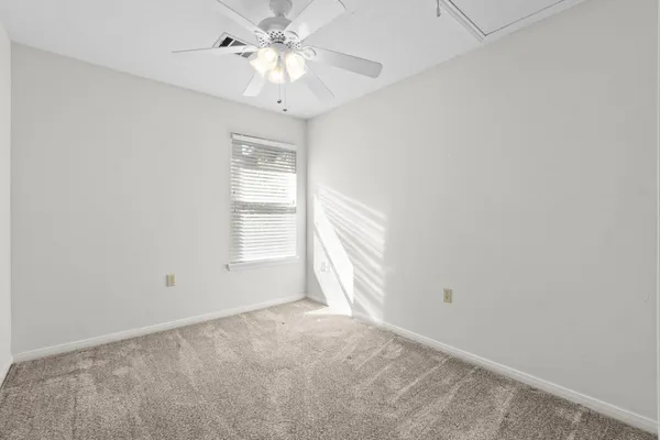 an empty room with a chandelier fan and windows