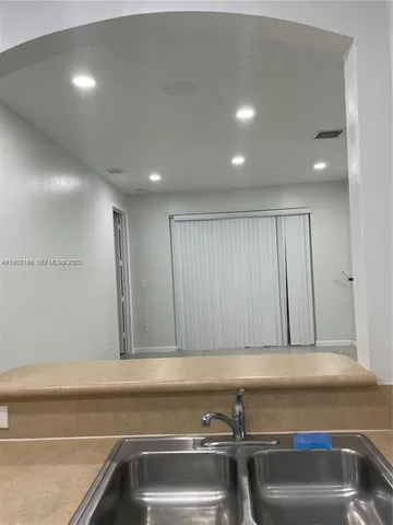 an empty room with windows and chandelier fan