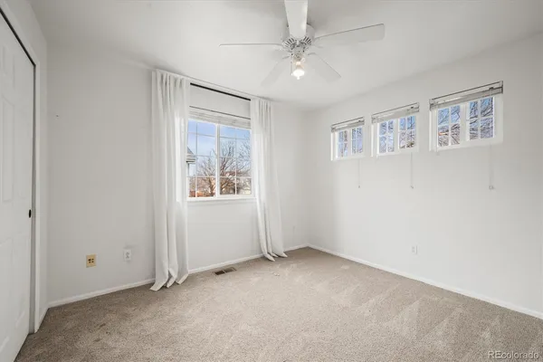 an empty room with windows and fan