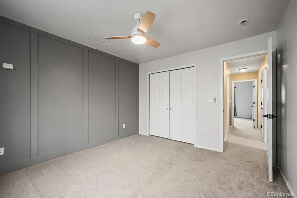 an empty room with closet and a chandelier fan