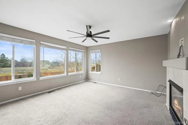 a view of an empty room with a window and a kitchen