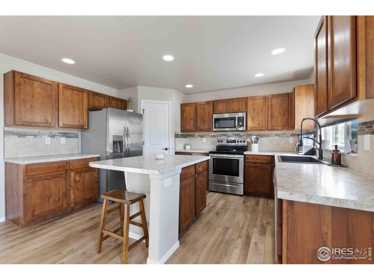 522 Lowland Street Severance, CO 80550 - Photo 1 of 30 a kitchen with stainless steel appliances granite countertop wooden cabinets a sink a stove a dining table and chairs