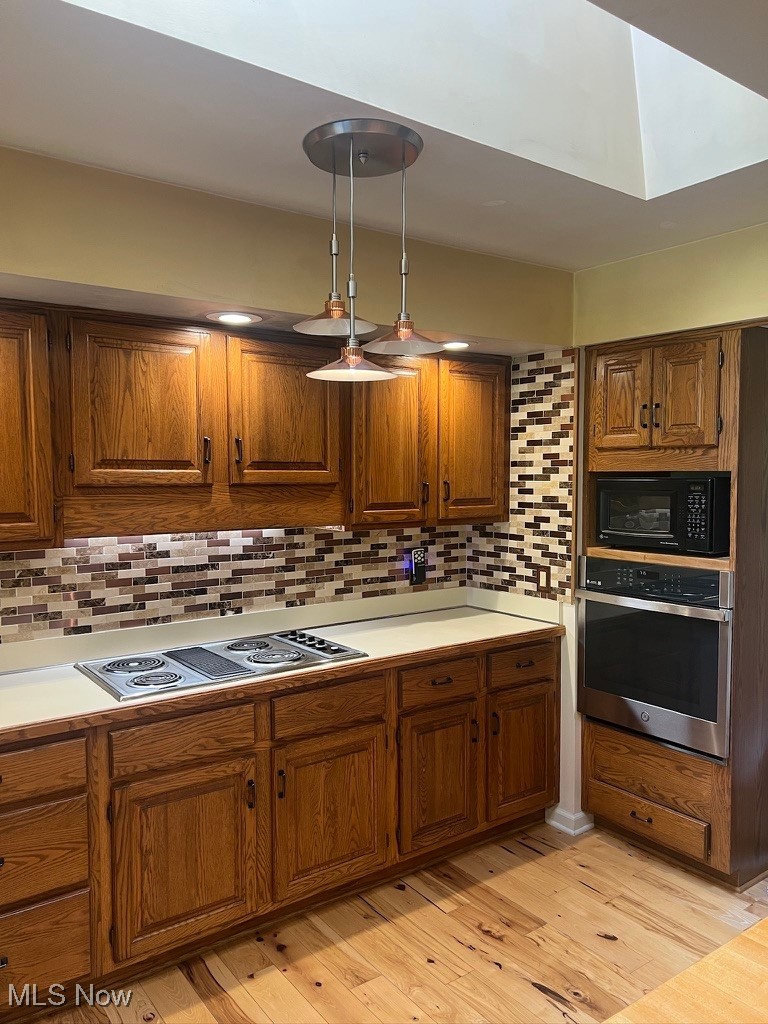 11331 Palmer Road Painesville, OH 44077 - Photo 9 of 47 Kitchen featuring light wood-type flooring, hanging light fixtures, stainless steel appliances, and backsplash