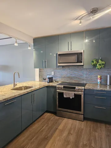 a kitchen with stainless steel appliances granite countertop a sink and stove top oven