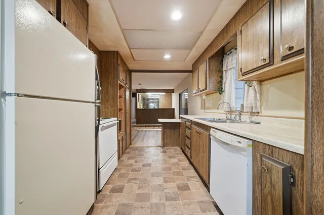 a large kitchen with stainless steel appliances granite countertop a refrigerator a sink dishwasher a oven with wooden cabinets