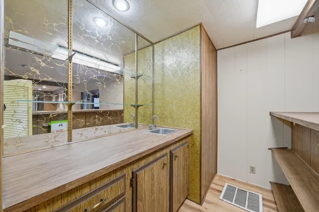 a bathroom with a granite countertop sink a mirror and shower