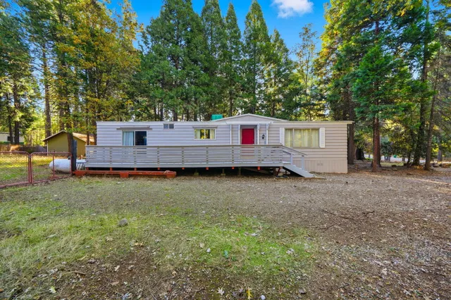 a view of a backyard with wooden fence and large trees