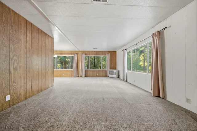 a view of a big room with windows and chandelier fan