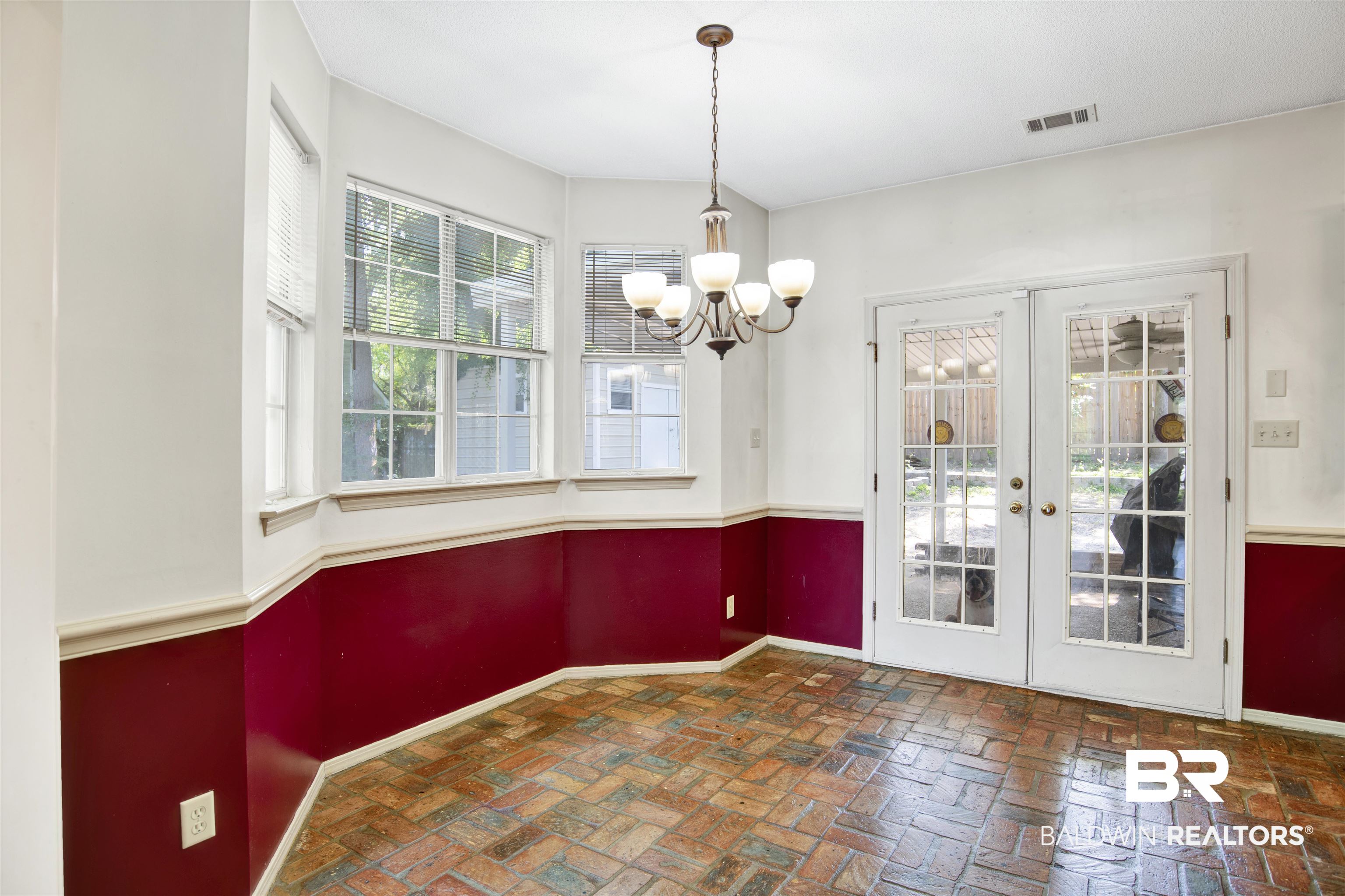 3412 Peyton Court Mobile, AL 36695 - Photo 9 of 27 Unfurnished dining area with baseboards, a chandelier, french doors, and brick floors