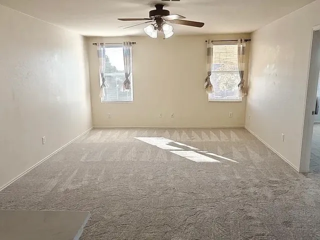 an empty room with windows and fan