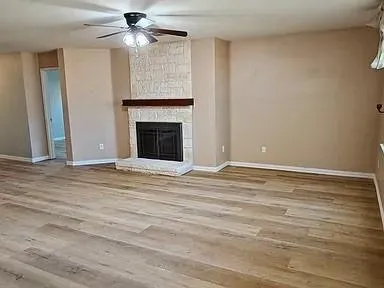 a view of an empty room with a fireplace and a chandelier fan