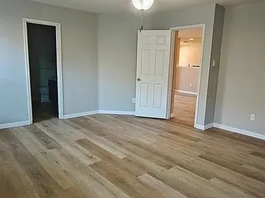 an empty room with wooden floor and closet area