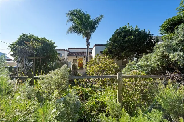 a backyard of a house with table and chairs plants and large tree