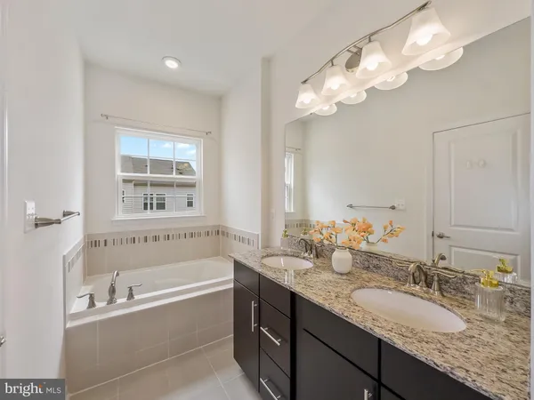 a bathroom with a granite countertop bathtub a sink and a mirror