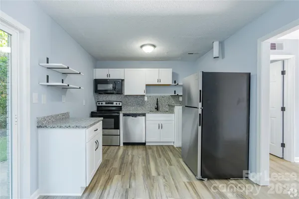 a kitchen with granite countertop appliances a sink and a refrigerator