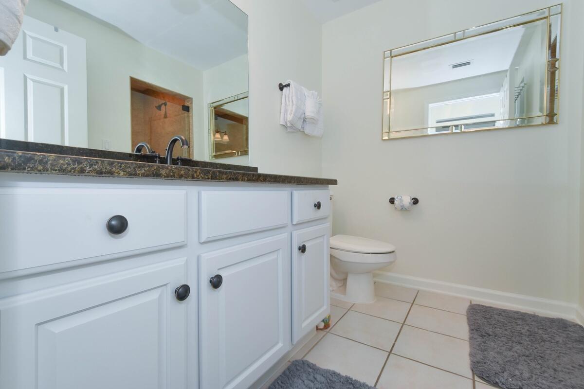 1050 Highway 98, Unit 905E Destin, FL 32541 - Photo 18 of 30 a bathroom with a granite countertop sink a toilet mirror and vanity