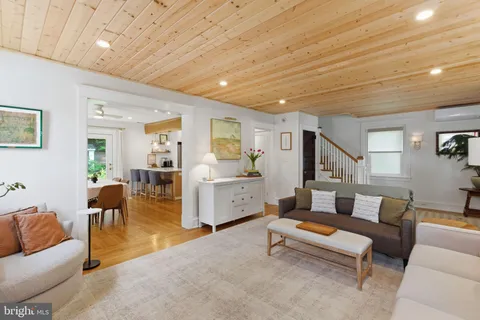 a living room with furniture and a dining table with wooden floor