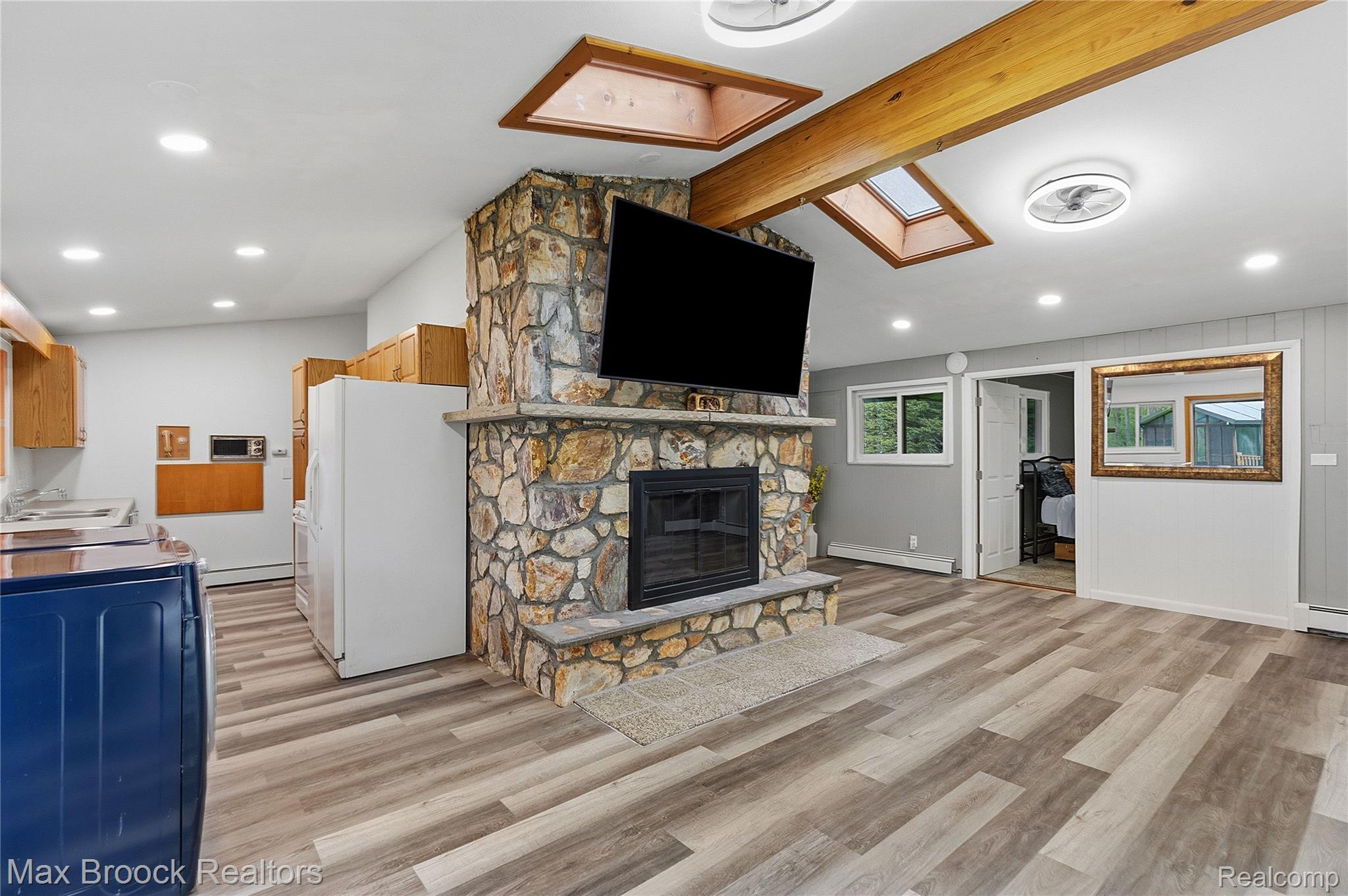 1392 Maple Grove Road Lapeer, MI 48446 - Photo 23 of 70 Living area with a fireplace, light wood-type flooring, baseboard heating, a skylight, and lofted ceiling with beams