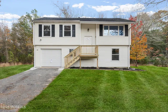 a view of a yard in front of a house with large windows