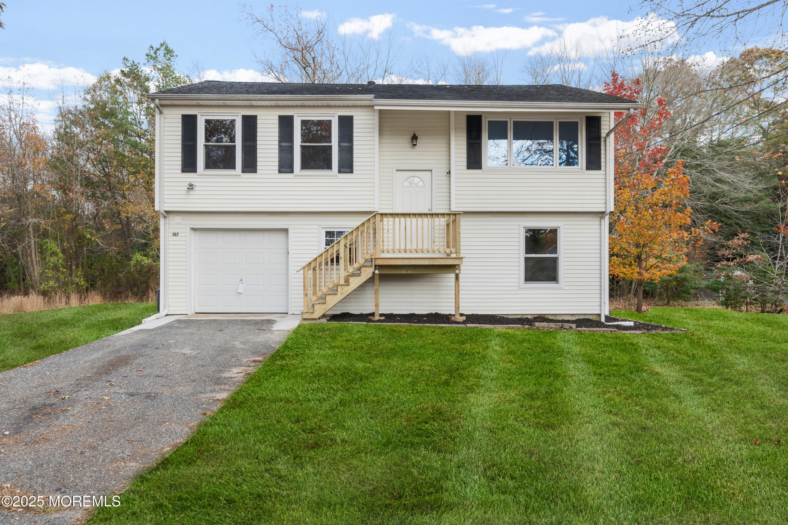 a view of a yard in front of a house with large windows