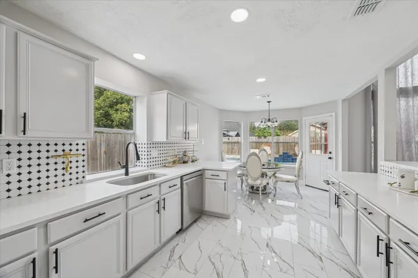 a large white kitchen with lots of counter space dining table and chairs