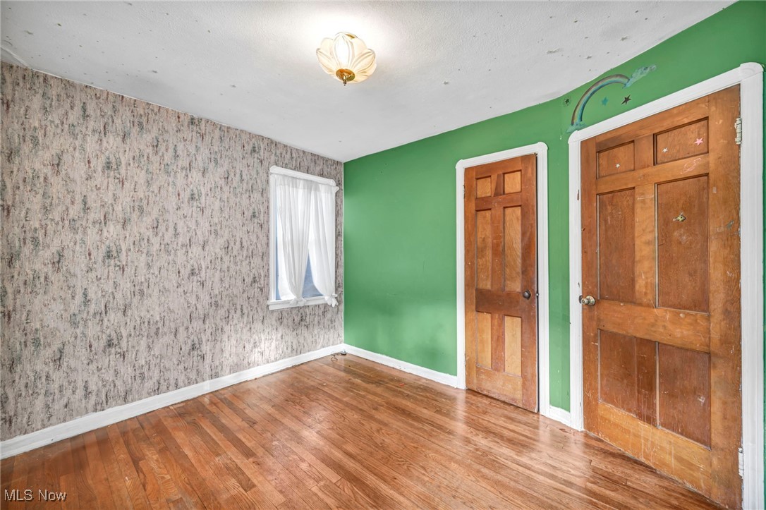 8017 Ackley Road Parma, OH 44129 - Photo 21 of 43 Unfurnished bedroom with wood-type flooring and wallpapered walls