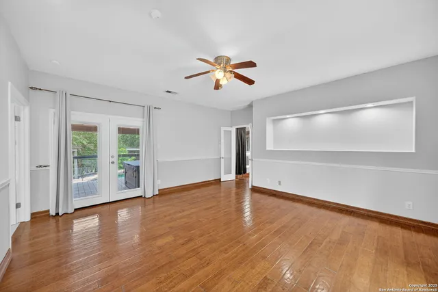 a view of empty room with wooden floor and fan