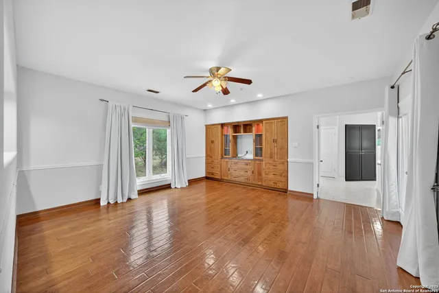 a view of a room with wooden floor and a ceiling fan