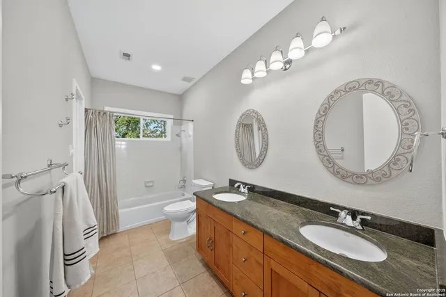 a spacious bathroom with a granite countertop double vanity sink a mirror and a toilet