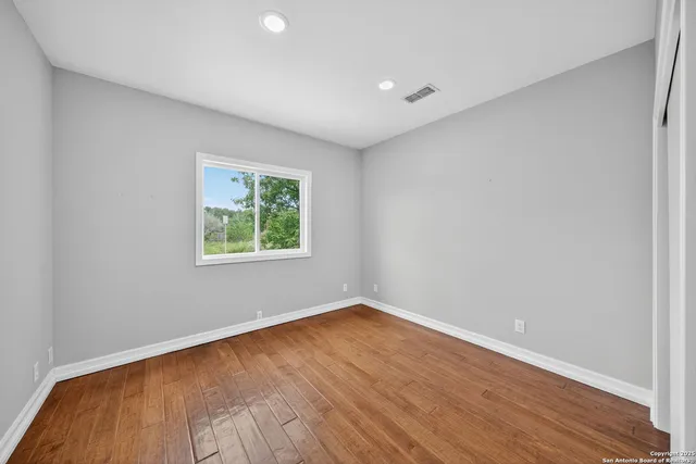 an empty room with wooden floor and windows