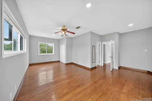 a view of an empty room with a window and wooden floor