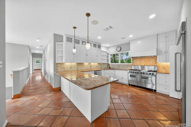 a large kitchen with kitchen island a large counter top stainless steel appliances and cabinets