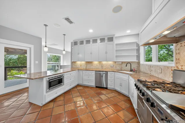 a large kitchen with stainless steel appliances granite countertop a stove and a sink
