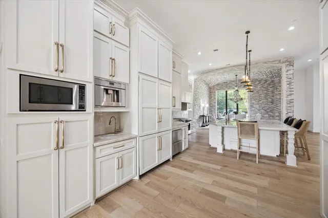 a large kitchen with kitchen island a stove a sink a center island and a wooden floor