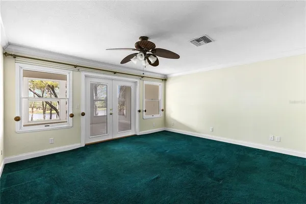 a view of an empty room with window and kitchen view