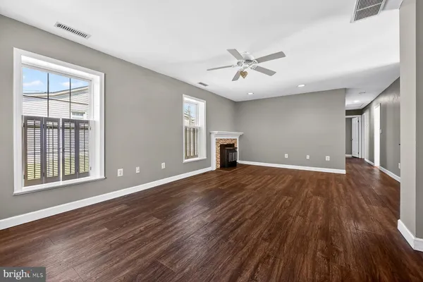 a view of an empty room with wooden floor fireplace and a window