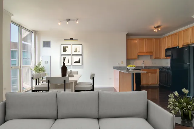 a living room with furniture kitchen and a refrigerator
