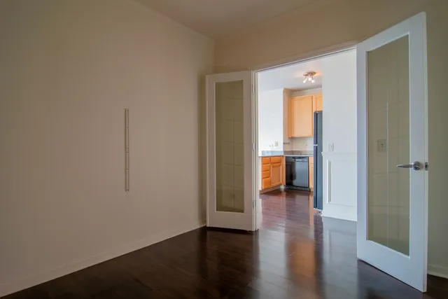 a view of a hallway with wooden floor and a bathroom