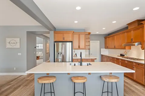 a kitchen with stainless steel appliances granite countertop a sink a stove and cabinets