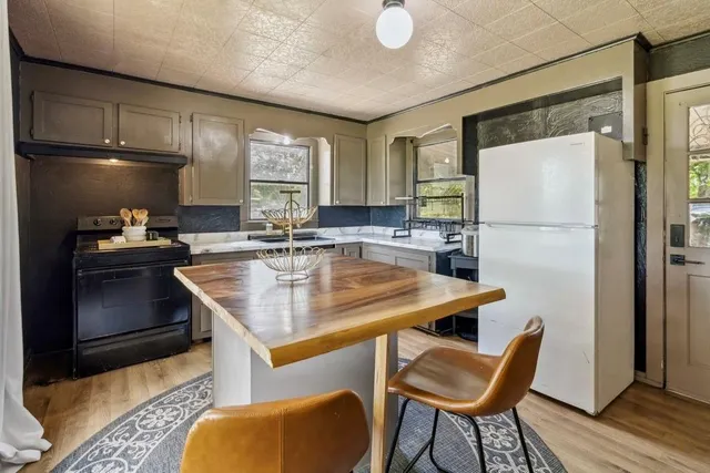 a kitchen with stainless steel appliances granite countertop a refrigerator a oven a sink a dining table and chairs with wooden floor