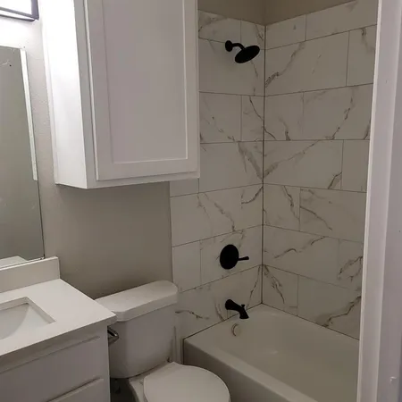 a bathroom with a toilet a sink a mirror and shower