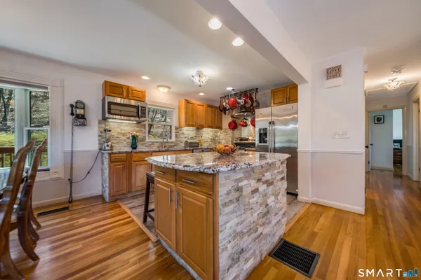 a kitchen with stainless steel appliances kitchen island granite countertop a stove refrigerator and cabinets