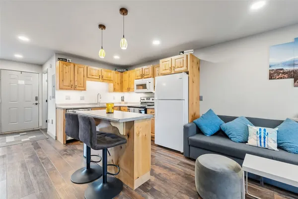 a kitchen with stainless steel appliances granite countertop a refrigerator a sink dishwasher a dining table and chairs with wooden floor