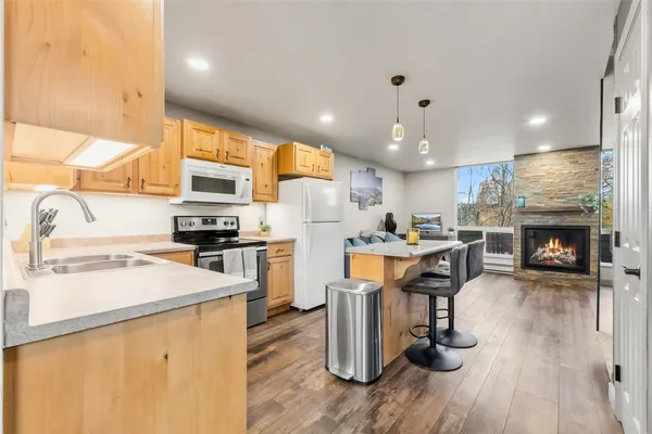 a kitchen with a refrigerator a stove top oven a sink dishwasher and a dining table with wooden floor