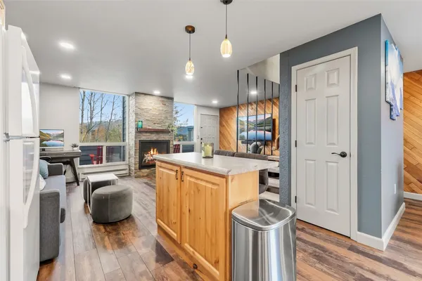 a view of a kitchen with kitchen island wooden floors and stainless steel appliances