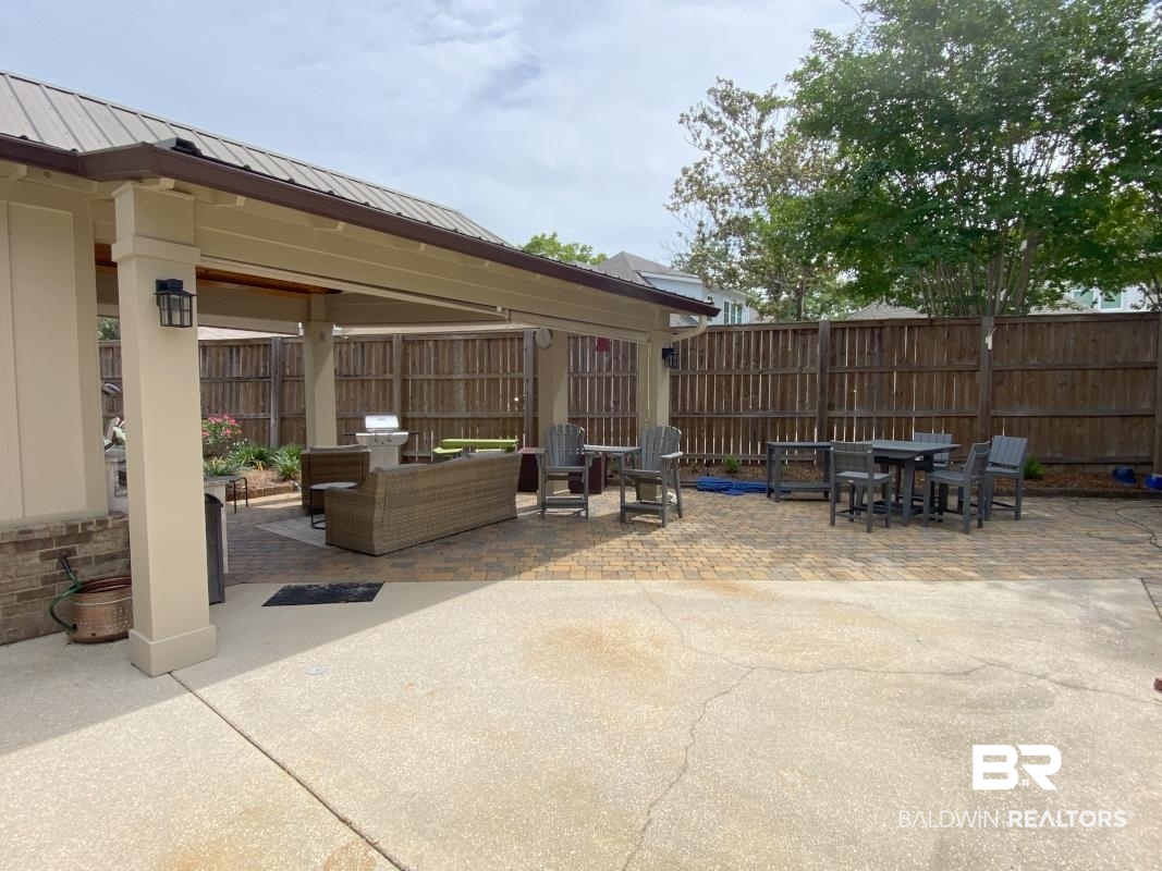 28888 Canal Road, Unit 77 Orange Beach, AL 36561 - Photo 16 of 23 Expansive outdoor living area featuring a covered patio with a metal roof, an exposed aggregate concrete slab, and a paver patio area